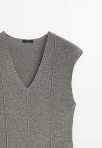 Gilet sans manches en maille grise avec col en V et détails de coutures verticales, étalé à plat sur un fond blanc.