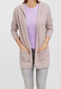 Ljusrosa cardigan med huva, som har två framfickor och ribbade ärmar, lagd över en lilafärgad figursydd topp och matchad med ljusa jeans.