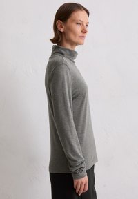 Grauer Langarmrollkragenpullover aus einem weichen, leichten Strick. Besitzt eine taillierte Silhouette und gerippte Bündchen, mit einer glatten Textur.