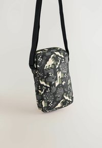 Sort og grå mønstret crossbody taske med lynlås lukning, der har en struktureret overflade og justerbar rem for praktisk bæring.