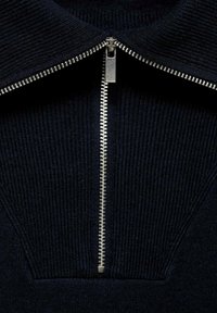 Námořnický svetr s texturou a vysokým límcem, stříbrným zipem. Tkanina má vroubkované detaily a strukturovaný design u výstřihu.