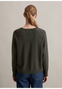 Mörkgrön tröja i mjukt material, med rundad halsringning, ribbade ärmslut och en avslappnad passform med en något cropped nederkant.
