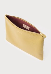 Sárga bőrtok texturált felülettel, cipzáras záródással és bordó béléssel, belül egy kis márkajelzéssel.