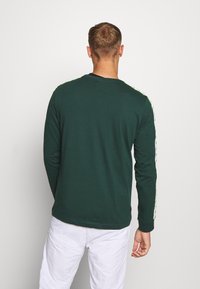 Långärmad grön skjorta i bomull, med kontrasterande vita sidostråk, rund halsringning och en avslappnad passform.