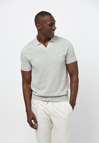 Grå kortärmad polo med V-ringning. Mjuk känsla och tuff passform. Kombineras med ljusa byxor.