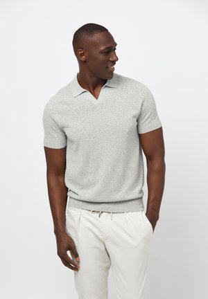 Camisa polo gris de manga corta con diseño de cuello en V. Textura suave y estilo ajustado. Combinada con pantalones de color claro.