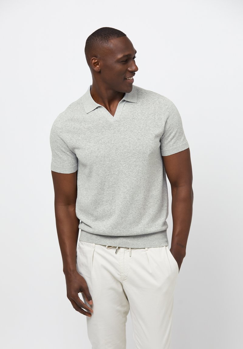 Grå kortärmad polo med V-ringning. Mjuk känsla och tuff passform. Kombineras med ljusa byxor.