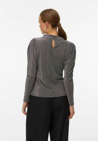 Ilga rankovė palaidinė metalizuotos pilkos spalvos audinyje su subtiliu blizgesiu, su pūstomis petnešomis ir raktu skylutė nugaros dalyje.