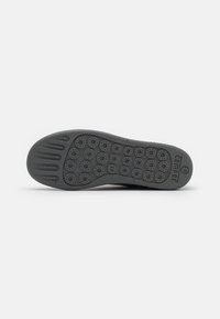 Semelle de chaussure noire montrant des motifs circulaires d'adhérence, taille 41 marquée près du centre et nom de la marque « Camper » près du talon.