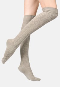 Chaussettes côtelées hauteur genou de couleur beige clair avec une texture douce, présentant un ajustement serré et une zone de orteil renforcée.