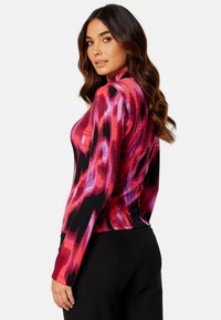 Langarmshirt in een levendig abstract patroon van rood, roze en zwart; geribbelde textuur; aansluitend ontwerp; ronde halslijn.