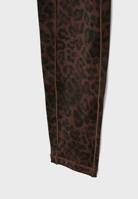 Hnědé legíny s leopardím potiskem vyrobené z elastického materiálu, s černými skvrnami, plochými švy a přiléhavým střihem.