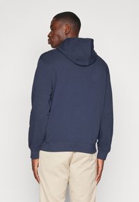 Felpa con cappuccio blu navy con cordino, polsini e orlo a coste. Realizzata in materiale morbido, presenta un design pulito e semplice senza grafiche.
