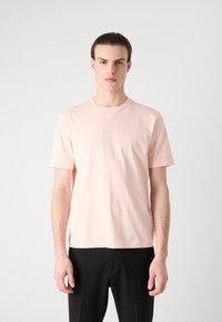 Lyserød bomulds t-shirt med rund hals og korte ærmer, der har et lille "BOSS" logo foran. Glat tekstur.
