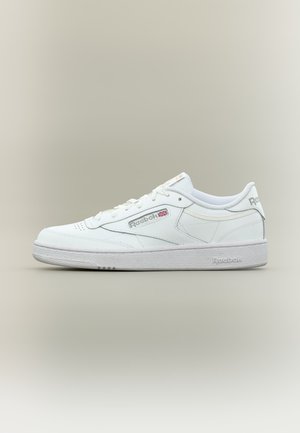 Basket basse blanche Reebok avec lacets blancs, semelle texturée et logo Reebok avec un petit drapeau britannique sur le côté.