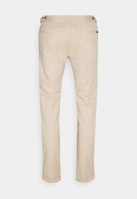 Beige Chinos mit geradem Bein, Fronttaschen und Knopfdetails. Hergestellt aus Baumwollstoff mit glatter Textur.