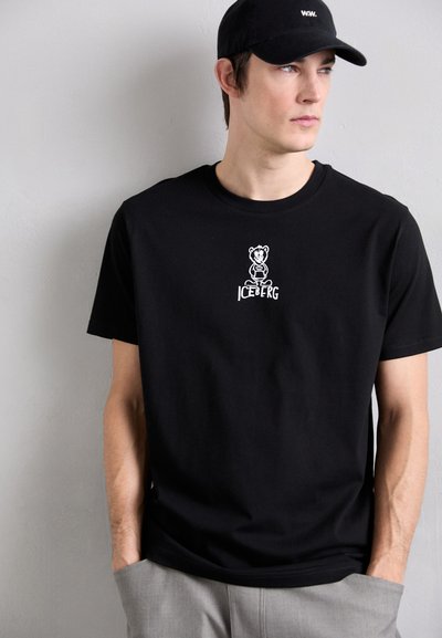 T-shirt en coton noir avec un graphique de ours brodé et le texte "ICEBERG" au centre, design à col rond et manches courtes.