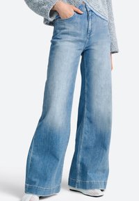 Svetlomodré džínsy širokého strihu z denimu, s vysokým pásom, prednými vreckami a mierne opraným vzhľadom s hladkým povrchom.