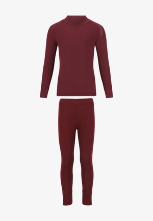 Bordeaux lange mouwen top en legging, gemaakt van zachte stof. Roze en kastanjebruine sokken met manchetaccenten. Kind staat, handen samengevouwen.