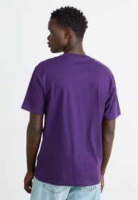 T-shirt violet à manches courtes en coton, avec un col rond et une coupe décontractée, présenté de dos avec un design uni.