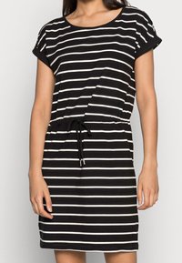 Robe rayée noire et blanche à manches courtes, avec un col rond et une taille à cordon pour un ajustement réglable. Fabriquée en tissu doux.