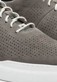 Szare perforowane sneakersy skórzane z białymi sznurowadłami i teksturowaną gumową podeszwą. Podkreślone szwy dodają szczegółu do designu butów.