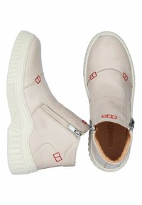 Beige ankle boots with a smooth leather finish, featuring red stitching accents, a side zipper, and a white textured sole.