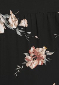 Kukkaiskuvioinen musta kangas, jossa on pehmeitä vaaleanpunaisia ja kermaisia kukkia vihreillä lehdillä. Sileä rakenne yläosassa tuo lisäyksityiskohtia.