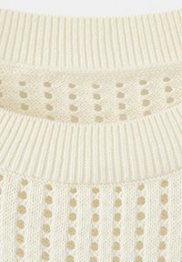 Nahaufnahme eines cremefarbenen Strickpulloverkragens mit geripptem Ausschnitt und vertikalem, offen gestricktem Streifenmuster.