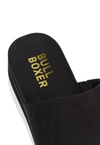 Sandale noire à glissière avec une texture douce, présentant un lettrage doré audacieux "BULL BOXER" sur le dessus et une semelle plateforme blanche.