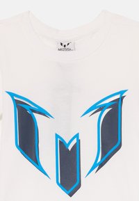 T-shirt en coton blanc avec un design graphique bleu et gris foncé formant une lettre "M" stylisée sur le devant. Étiquette visible à l'intérieur du col.