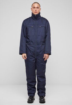 Navy blue insulated coverall with a high collar, front zipper, and two chest pockets. Made from durable, smooth fabric. Features long sleeves.