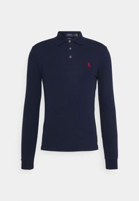 Polo de manga larga en color azul marino, fabricado en algodón, con una tapa de tres botones, puños acanalados y un pequeño logo rojo en el lado izquierdo del pecho.