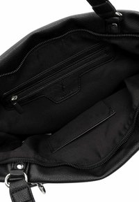 Intérieur d'un sac à main en cuir noir, avec une poche zippée et une poche plate. Matériau texturé avec doublure en tissu doux, design minimaliste.