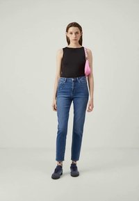 Juoda be rankovių palaidinė, mėlynų džinsų aukštu liemeniu, purpuriniai sportbačiai ir maža rožinė per petį nešama rankinė. Paprastas dizainas su minimaliais akcentais.