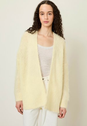 Cardigan long, à ouverture frontale, en tissu jaune doux et duveteux. Présente une coupe décontractée avec des manches larges et une finition texturée.