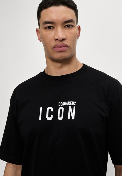 Sort t-shirt lavet af bomuld med rund halsudskæring. Foran er der hvidt trykt tekst: "DSQUARED2 ICON," med fed skrift.