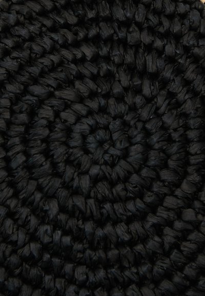 Tappeto tessuto nero con un design circolare. La texture è ruvida con materiale spiegazzato, mettendo in evidenza un motivo a spirale in tutto il tappeto.