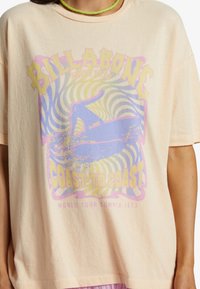 Perzikkleurig oversized katoen t-shirt met een ronddraaiend ontwerp met surflook, gele en paarse tekst en een ontspannen halslijn.