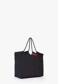 Borsa tote in tessuto nero con doppie maniglie e interno rosa a contrasto. Presenta un design minimalista e un'apertura superiore senza chiusura.