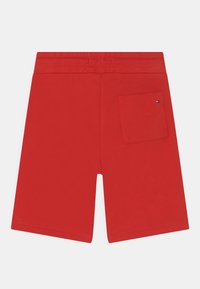 Calções de algodão vermelhos com cintura elástica, bolsos laterais e um único bolso nas costas com um pequeno detalhe de logotipo. Textura suave.
