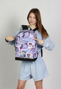 Mochila morada con personajes de princesas animadas, texto "Una vez en un sueño", fondo negro, correas ajustables y cierre con cremallera.