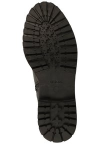Semelle en caoutchouc noir avec des motifs en relief multidirectionnels, perforations circulaires pour la respirabilité et un logo en relief sur le côté.