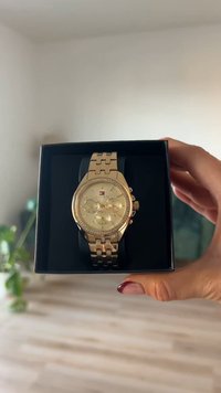 Orologio oro con cassa rotonda, tre sottodial e lunetta con cristalli. Bracciale in metallo con maglie intrecciate. Presentato in una scatola nera.