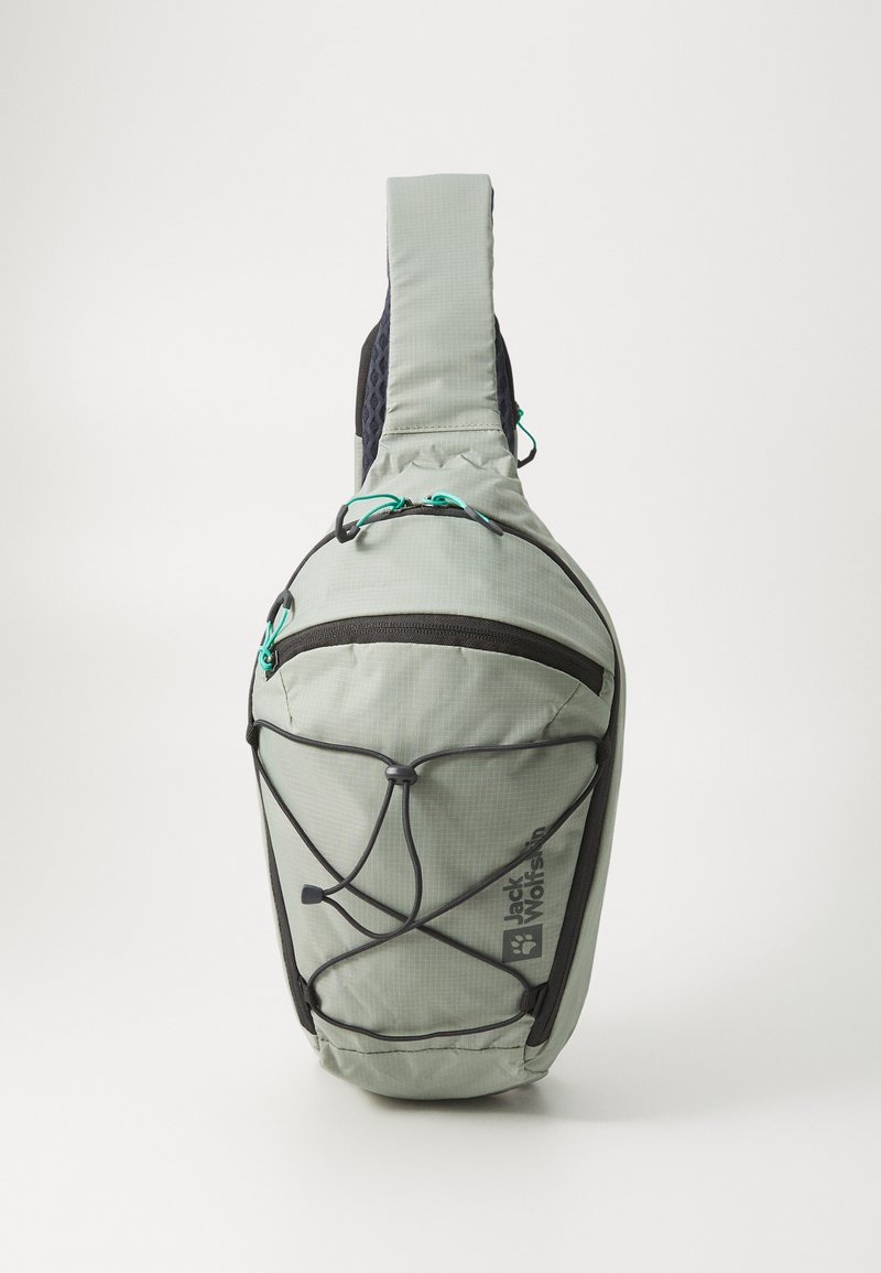 Crossbody-ryggsäck i ljusgrön tyg. Har ett zippered huvudfack, bungee-korddetaljer och vadderad axelrem.