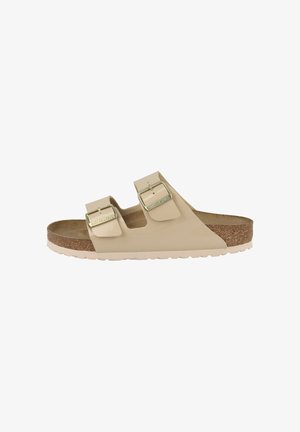 Beige Birkenstock Sandale mit zwei verstellbaren Riemen, Metall-Schnallen, Kork-Fußbett und weißer, strukturierter Sohle, Seitenansicht.