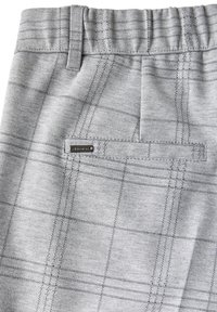Tissu gris à motif avec une poche arrière comportant une petite étiquette métallique de la marque et une taille élastique avec un passant de ceinture.