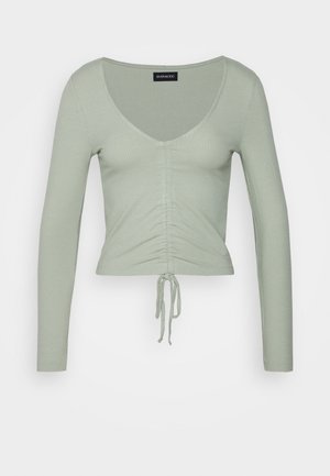 Top a maniche lunghe verde a coste con scollatura a V profonda, dettagli arricciati davanti e sistema di regolazione con cordino all'orlo.