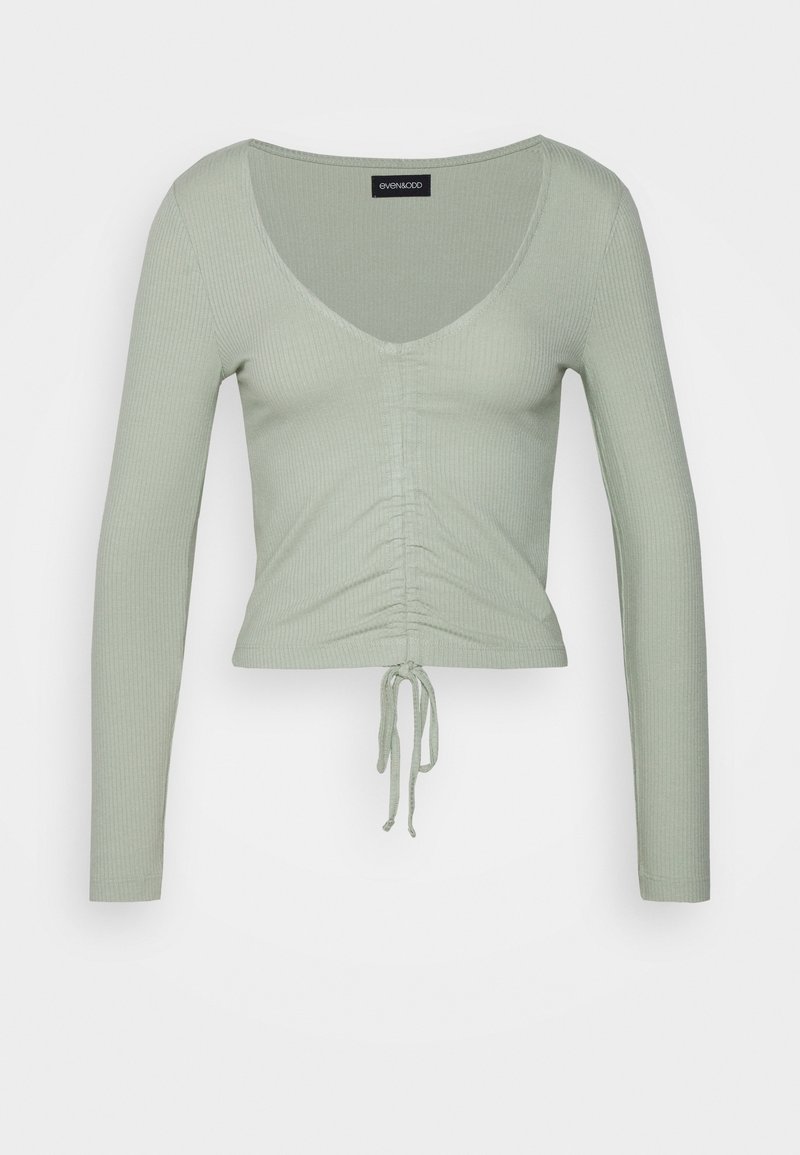 Langärmliges grünes Rippoberteil mit tiefem V-Ausschnitt, gerafftem Detail an der Vorderseite und verstellbarem Kordelzug am Saum.
