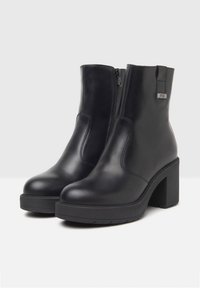 Black leather ankle boots with a chunky heel, featuring a side zipper, textured accents, and a smooth finish.